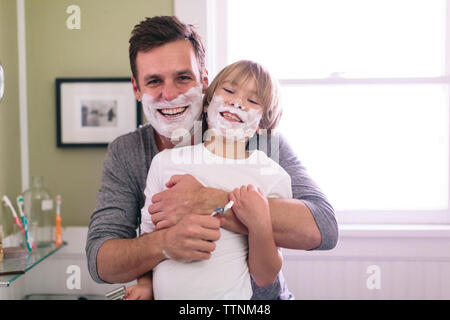 Portrait of happy father and son with shaving cream on face standing in bathroom Stock Photo
