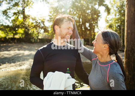 Happy woman pulling man's hair while standing by river Stock Photo