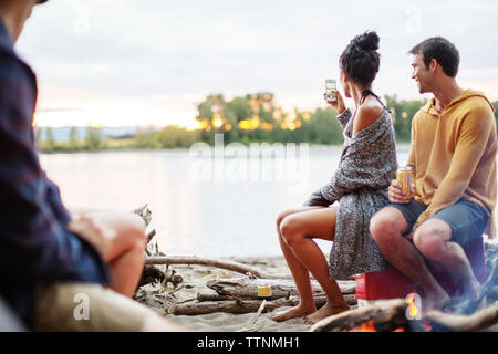 Friends at campfire against river Stock Photo