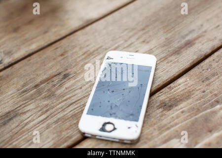 Close-up of smart phone with cracked screen on wooden table Stock Photo