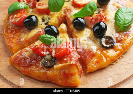 Sliced delicious pizza with olives on wooden plate, close up Stock Photo
