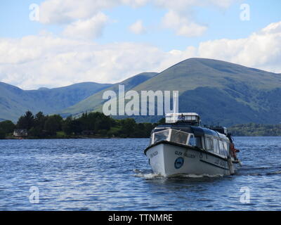 Picture postcard view of a sunny day on Loch Lomond with the Luss - Balmaha express boat, the Glen Falloch coming towards the pier at Balmaha. Stock Photo