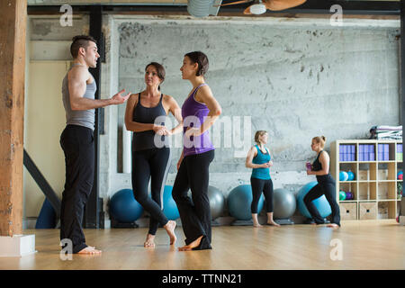 Male instructor guiding women in gym Stock Photo