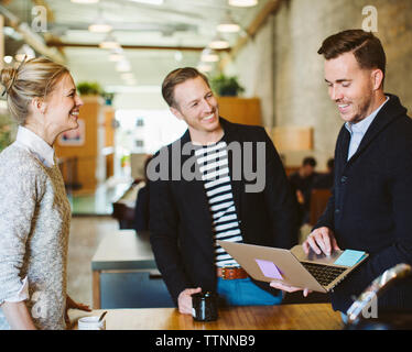businessman using laptop computer while standing with colleagues in office Stock Photo