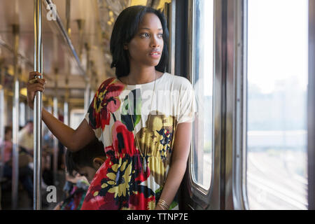 Thoughtful woman looking through window while travelling in train Stock Photo