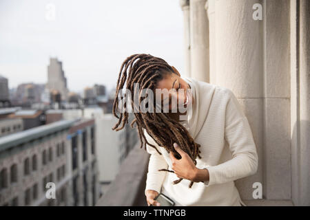 Happy woman playing with hair on balcony Stock Photo