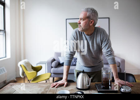 Thoughtful mature man looking away while preparing coffee in home Stock Photo
