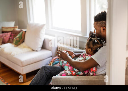 Side view of father using tablet computer with children in living room Stock Photo