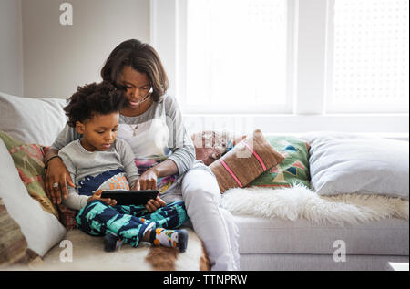 Mother and son using tablet computer on sofa at home Stock Photo
