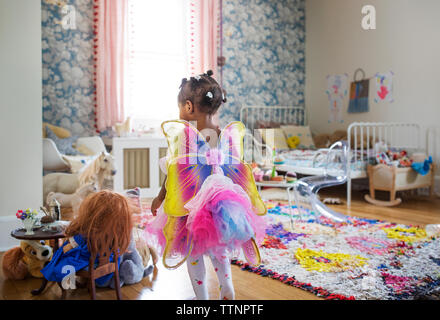 Rear view of girl dressed in fairy costume walking in bedroom Stock Photo