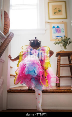 Rear view of girl in fairy costume moving up steps at home Stock Photo