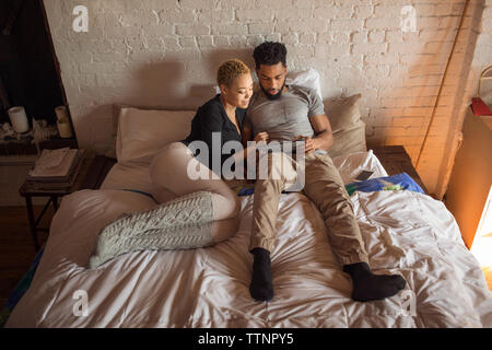 Overhead view of multi-ethnic couple using tablet computer on bed Stock Photo