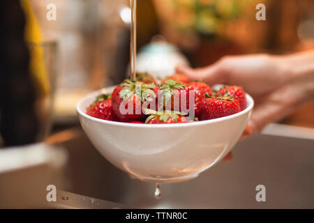 Cropped image of woman washing fresh strawberries in kitchen Stock Photo