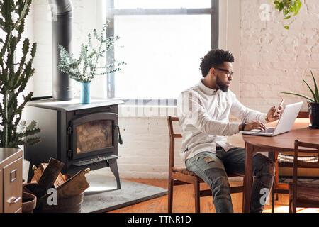 Young man using smart phone and laptop at home Stock Photo