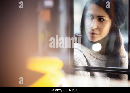 Thoughtful young woman seen through glass wall Stock Photo