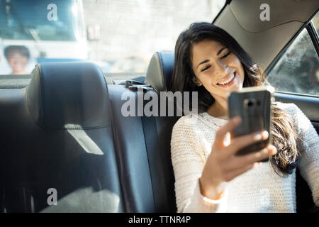 Happy young woman taking selfie through smart phone in taxi Stock Photo
