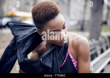 Sporty young woman wearing jacket at park Stock Photo