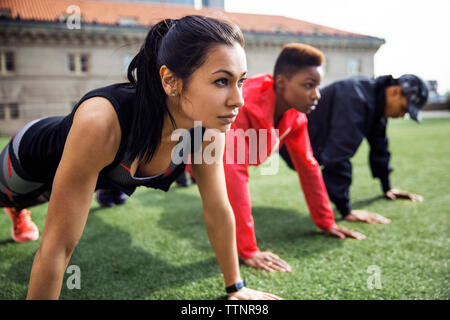 Determined athletes doing push-ups on grassy field Stock Photo