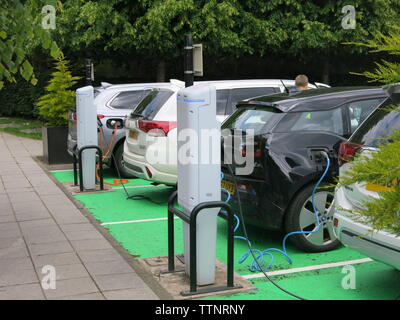 Photo of four cars at an electric car charging-point, where they have reversed up to the points and connected the plugs Stock Photo
