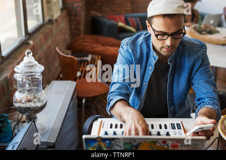 Man using mobile phone with piano at home Stock Photo