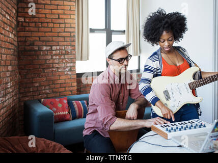 Friends playing musical instrument at home Stock Photo