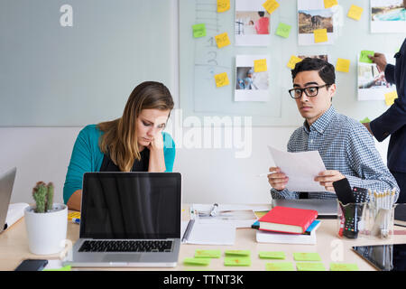 Surprised businessman working with colleague against whiteboard at office Stock Photo