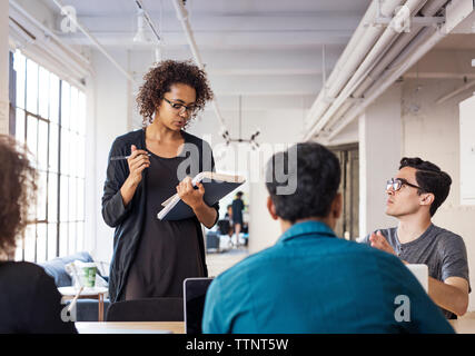 Confident businesswoman sharing ideas with colleagues during meeting in board room Stock Photo