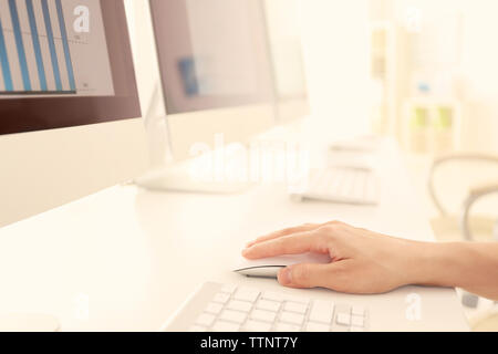Female hand holding mouse while working on computer Stock Photo