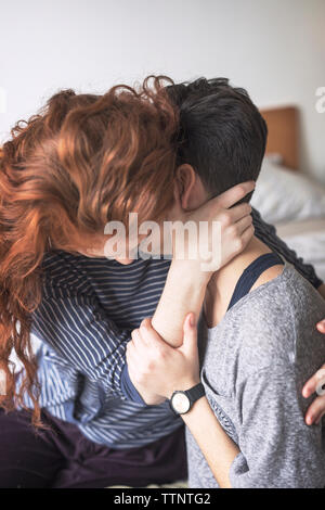 Close-up of romantic lesbians couple embracing on bed at home Stock Photo