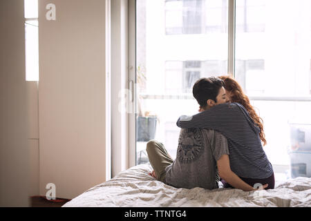 Romantic lesbians embracing while sitting on bed at home Stock Photo