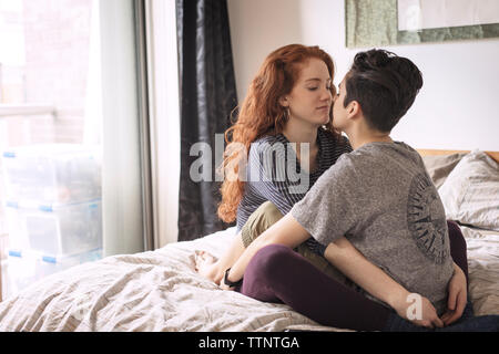 Lesbians romancing while relaxing on bed at home Stock Photo