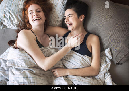 High angle view of cheerful lesbians relaxing on bed Stock Photo