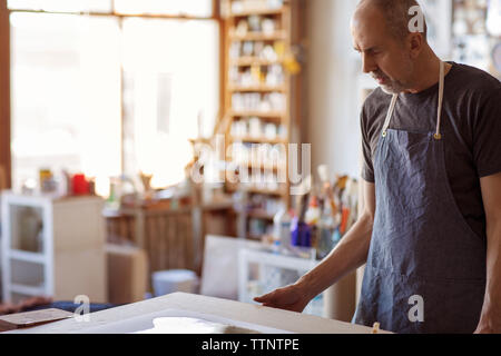 Male artist looking painting at table in workshop Stock Photo