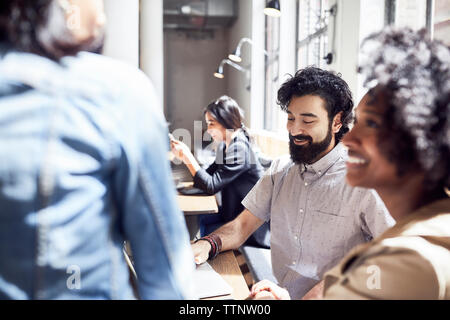 Happy business people having meeting with female colleague sitting in background Stock Photo