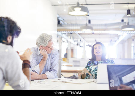 businessmen looking at female colleague explaining during meeting Stock Photo