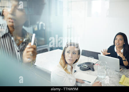 Female colleagues having discussion in office seen through window Stock Photo