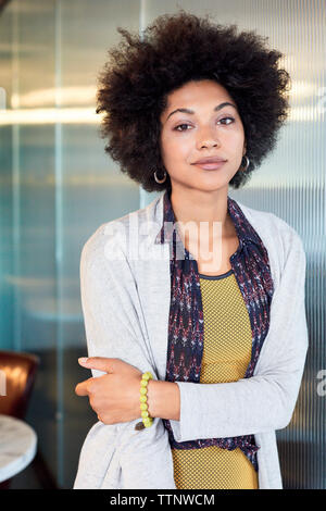 Portrait of confident businesswoman standing against window in office Stock Photo