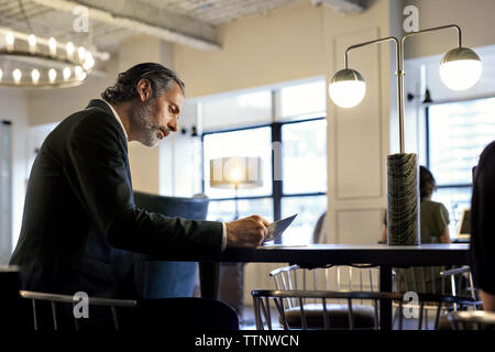businessman studying documents while sitting at creative office with female colleague in background Stock Photo