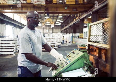 Side view of blue collar worker using control machine while working in steel industry Stock Photo