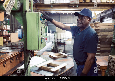 Side view of worker using machine while working in steel industry Stock Photo