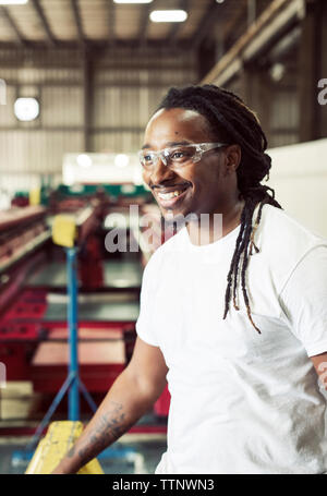 Cheerful blue collar worker wearing protective eyeglasses while working in steel industry Stock Photo