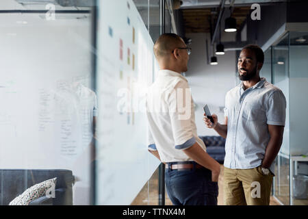 businessmen discussing while standing at corridor in office Stock Photo