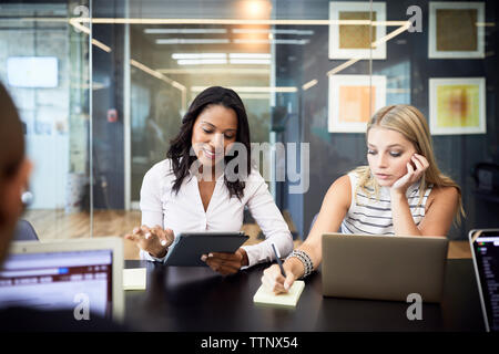 businesswomen using technologies while sitting in meeting at conference table Stock Photo