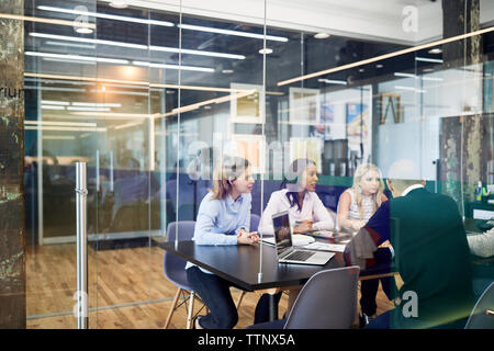business people at conference table during meeting seen through glass doors in office Stock Photo