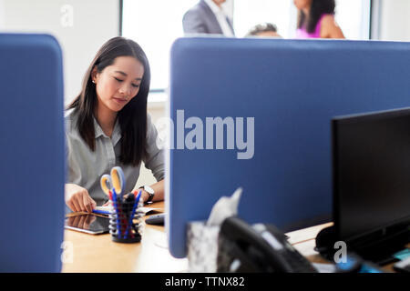 Confident businesswoman reading diary while sitting at desk in creative office Stock Photo