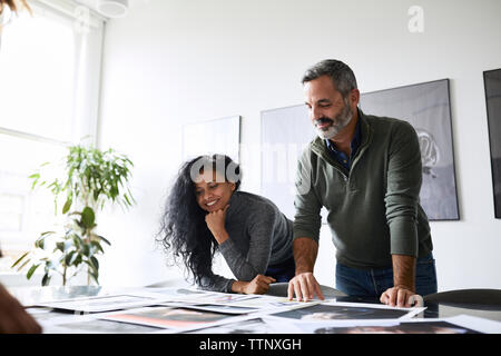 Low angle view of business people examining photograph printouts in conference room Stock Photo