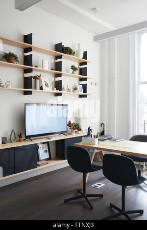 Shelves over television set by furniture in modern office Stock Photo