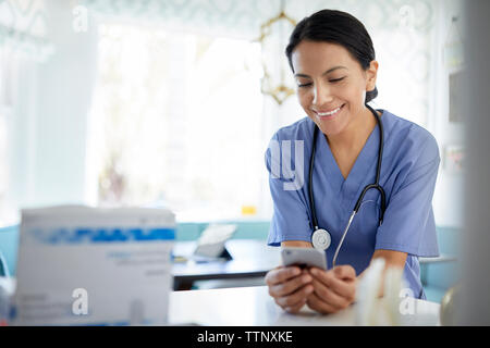 Smiling female doctor using smart phone while working in hospital Stock Photo