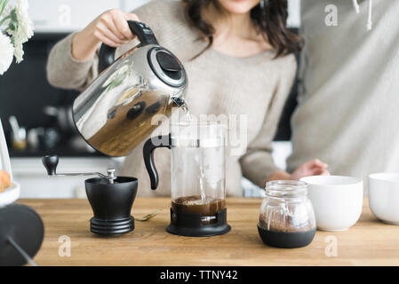 Midsection of woman with boyfriend making coffee at table in kitchen Stock Photo