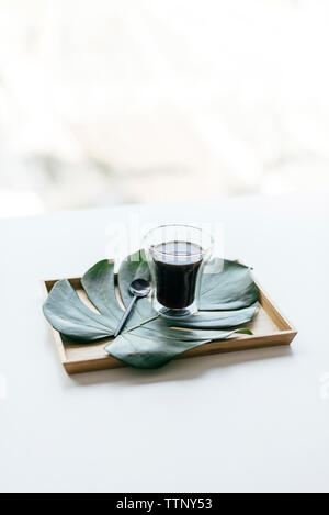 High angle view of coffee with monstera leaf in wooden tray on white background Stock Photo